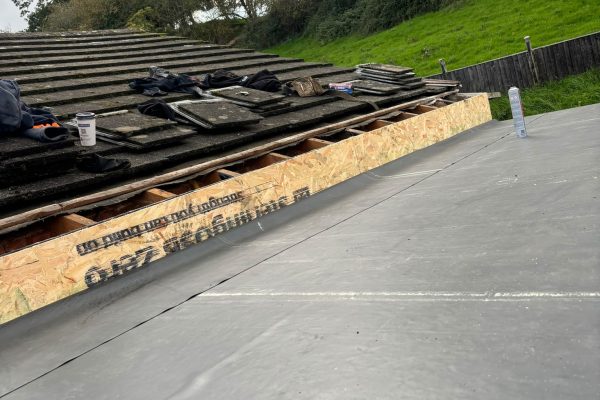 New rubber roof covering in St Asaph with work visible at the adjoining tiled roof.
